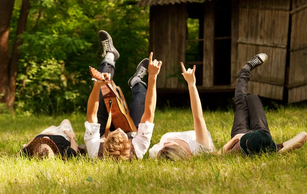 Vier Freunde, die im Gras liegend — Stockfoto