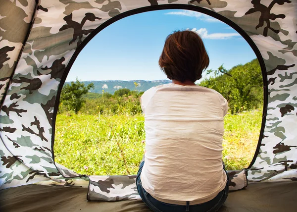 Girl sitting near open tourist tent door — Stock Photo, Image