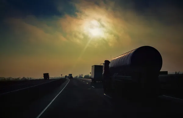 Camion-citerne d'essence monte la route sous le soleil du soir rayons — Photo