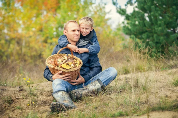 Отец и сын с полной корзиной грибов на лесной поляне — стоковое фото