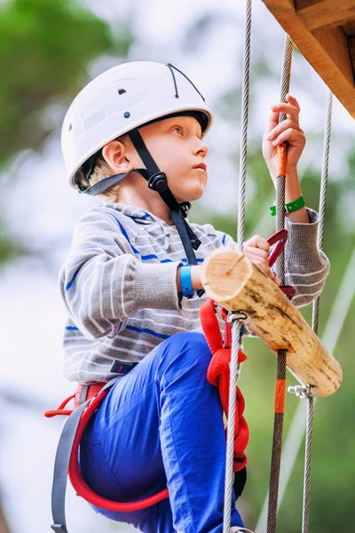 Rapaz, subindo a escada de corda no parque de adrenalina — Fotografia de Stock