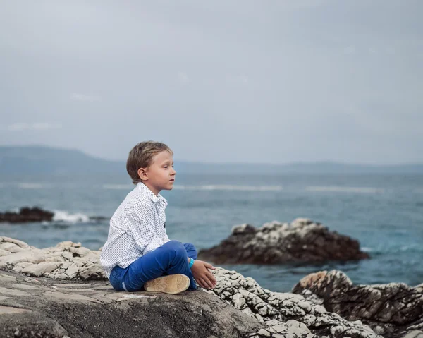 Niño sentado en una roca — Foto de Stock