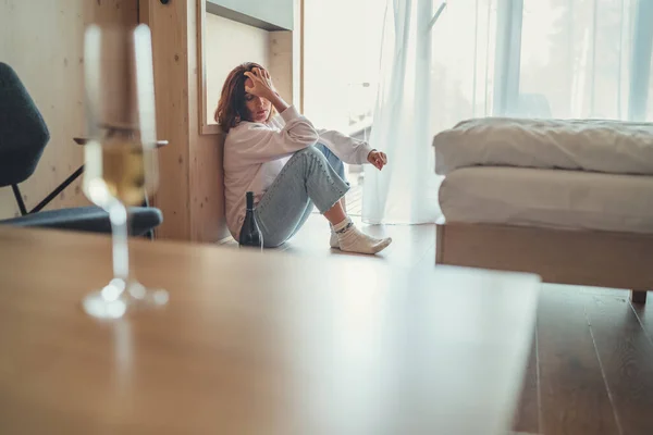 Üzgün Kadın Yatak Odasındaki Pencerenin Yanında Açık Bir Içki Şişesiyle — Stok fotoğraf