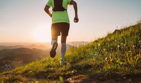 アクティブマウンテントレイルランナーは バックパック付きの明るいTシャツを着て 日没時に美しい丘によって耐久マラソンレースを実行しています スポーティアクティブ人バックライトのコンセプトイメージ — ストック写真