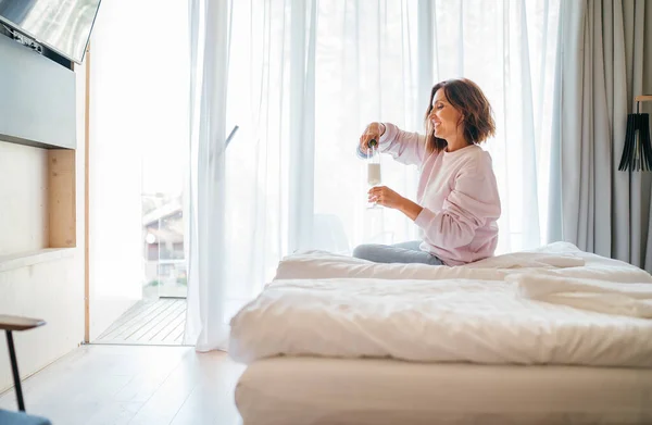 Lachende Frau Die Auf Dem Hotelzimmerbett Neben Dem Fenster Sitzt — Stockfoto