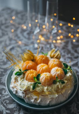 Pavlova pastası, adı taze mandalina, karamel, nane, physalis ve arkaplanda Noel ışıkları olan pudra şekeriyle süslenmiş Rus balerininden gelmektedir..