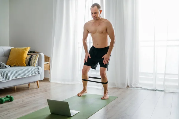 Spor Paspasına Oturmuş Sağlıklı Bir Adam Lastik Direnç Bandı Kullanarak — Stok fotoğraf