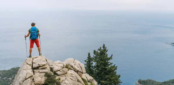 年轻的背包客男子使用远足的杆子 享受地中海在悬崖顶上的里昂路徒步行走 Letoon附近著名的Likya Yolu土耳其路线 主动度假的概念形象 — 图库照片