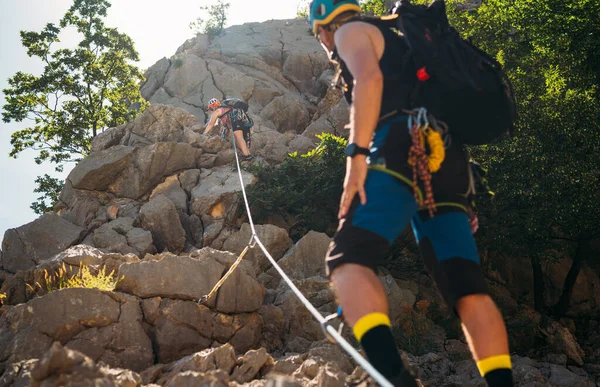 克罗地亚帕克莱尼察国家公园内 戴着防护头盔的男女攀登者和戴着攀登架的男子爬上了岩石墙上的悬崖 积极的极限运动时间概念 — 图库照片