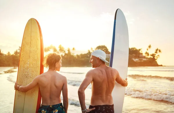 Vader Met Tienerzoon Staand Met Surfplanken Het Zandstrand Met Palmbomen — Stockfoto