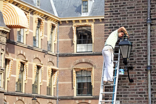 男は - オランダの議会の建物の前に修正するランプ t — ストック写真