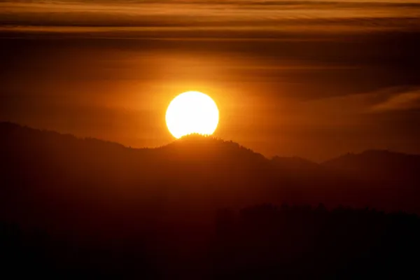 大きな太陽とオレンジの空 山のシルエット — ストック写真