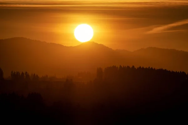 大きな太陽とオレンジの空 山のシルエット — ストック写真