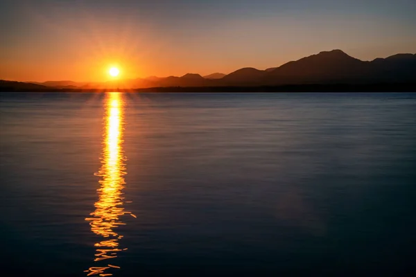Отражение Солнечных Лучей Поверхности Воды Солнце Силуэт Гор Заднем Плане — стоковое фото