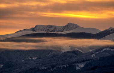 Karlı kış dağ manzarası ve renkli gökyüzü Slovakya 'daki Low Tatras dağlarındaki Dumbier tepesinin üzerinden doğuyor..