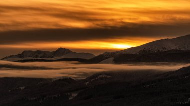 Karlı kış dağ manzarası ve Slovakya 'daki Dumbier ve Chopok tepelerinde gün doğumundan sonra renkli gökyüzü..