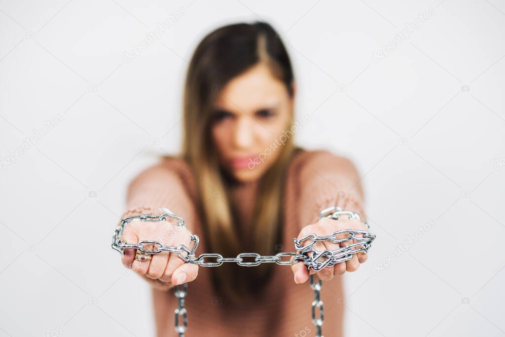 Hand of woman chained with iron chain on white background