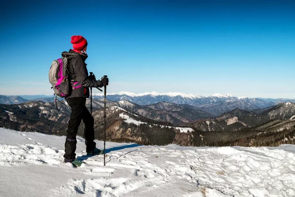 Kobieta Turysta Kijkami Trekkingowymi Patrząc Szczytu Śnieżnego Wzgórza Zimowej Wsi — Zdjęcie stockowe