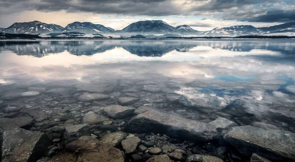 Slovakya 'daki Liptovska Mara barajının su yüzeyinde dağların ve karanlık gökyüzünün yansıması