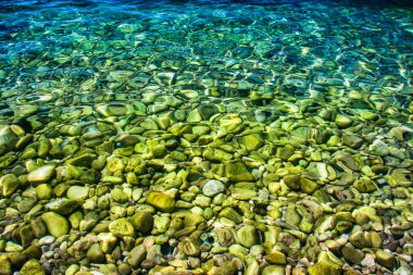 Kristal berrak ve turkuaz deniz suyu. Çakıl taşlı sahil