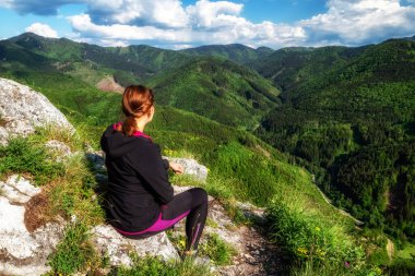 Yürüyüş yapan siyah elbiseli kız tepenin üstünde oturuyor ve dağlara bakıyor. Slovakya 'da Katova skala
