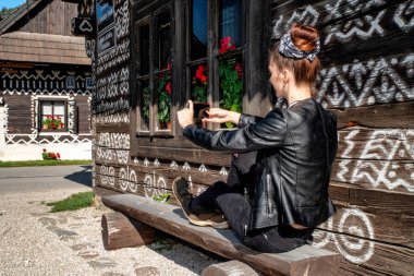 Güzel kız, tarihi V kırsalındaki ahşap kulübenin fotoğrafını çekiyor.