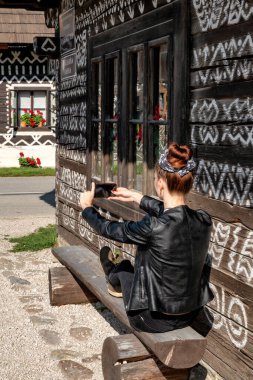 Güzel kız, tarihi V kırsalındaki ahşap kulübenin fotoğrafını çekiyor.