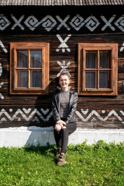 Slovakya 'nın Cicmany köyündeki eski ahşap kır evinin önünde poz veren güzel kız..