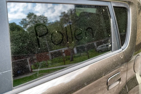 Text Pollen written on window of car. Allergy season.