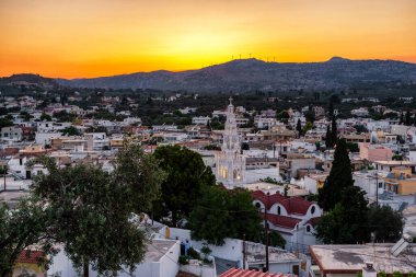 Yunanistan 'ın Rodos adasındaki Archangelos köyünün üzerinde renkli turuncu akşam gökyüzü