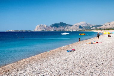 TRAGANOU, GREECE - 1 Temmuz 2022: Yunanistan 'ın Rodos adasındaki çakıl taşı Traganou plajında dinlenen tatilciler