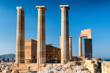LINDOS, GREECE - JULY 1, 2022: Tourists in front of Doric temple of Athena Lindia in Lindos acropolis in Rhodes island in Greece