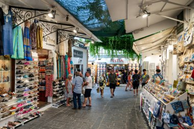 LINDOS, GREECE - 1 HAZİRAN 2022: Rodos adasındaki Lindos kasabasında hediyelik eşyalarla gezen ve bakınan turistler