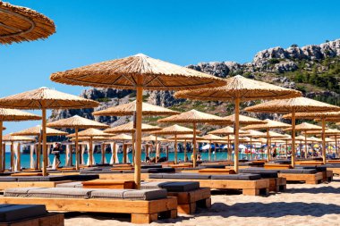 TSAMBİKA, GREECE - 2 Temmuz 2022: Yunanistan 'ın Rodos adasındaki Tsambika plajında tatilciler için güneş gözlüğü altındaki dinlenme yerleri