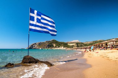 TSAMBİKA, GREECE - 2 Temmuz 2022: Yunanistan 'ın Rodos adasındaki Tsambika plajında Yunan bayrağı sallamak