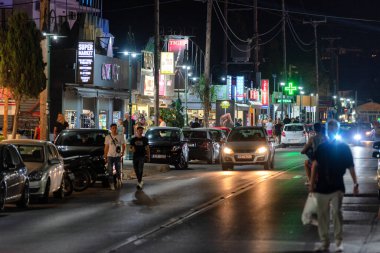 FALIRAKI, GREECE - JULY 3, 2022: Nightlife in resort Faliraki at Rhodes island. Tourist walking along the main street.