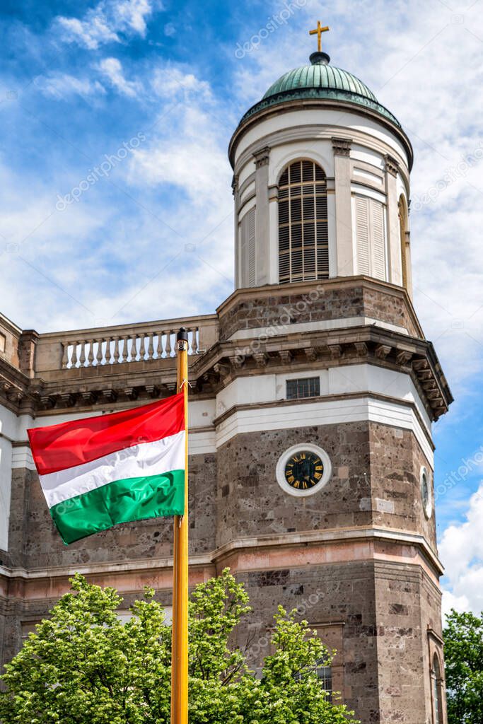 Waving hungarian flag on mast. Esztergom basilica at background