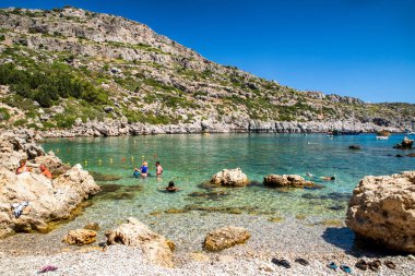 FALIRAKI, GREECE - JULY 4, 2022:People swimming in sea at famous Anthony Quinn Bay with crystal clear water in Rhodes island.