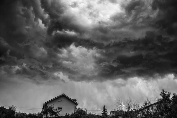 Dark stormy clouds over house on the hill