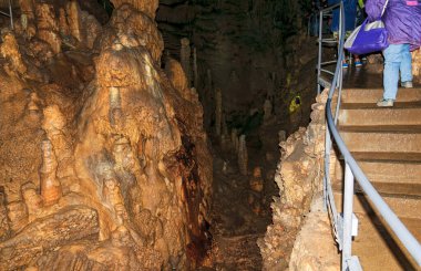A woman, a member of a tourist group, poses against the backdrop of a cave. Emine-Bair Khosar cave. Mammoth karst cave.