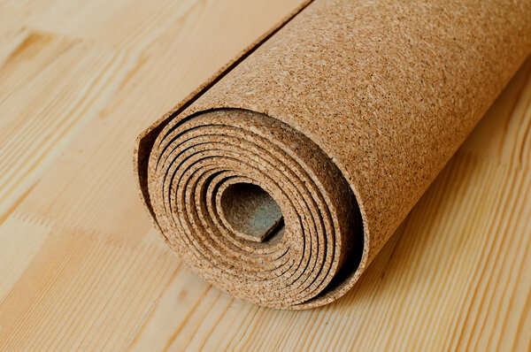 A roll of cork lies on the wooden floor