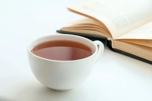 Taza de té negro y algunos libros para leer tumbados sobre la mesa — Foto de Stock