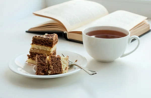 Чашка чаю, торта і деякі книги, щоб читати лежачи на столі Ліцензійні Стокові Зображення