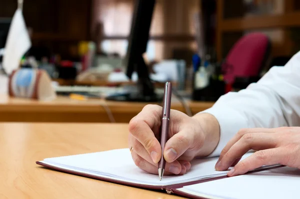 L'homme écrit quelque chose sur un livre blanc. Travaux de bureau Images De Stock Libres De Droits