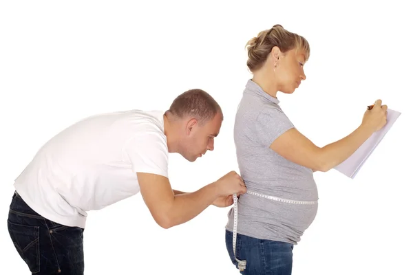 Husband measures wife's belly — Stock Photo, Image