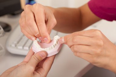 diş hekimi diş ipi kullanmayı gösteren hastasi