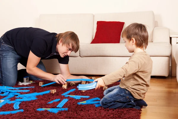 Papà sta giocando con il figlio nella ferrovia giocattolo — Foto Stock