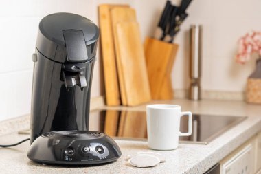 Kahve makinesi ve sehpanın üzerinde kahve yastıkları.