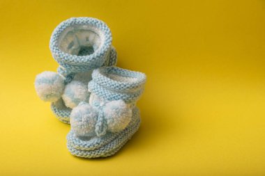 Sarı arka planda yeni doğan çocuklar için ev yapımı örgü ayakkabılar.