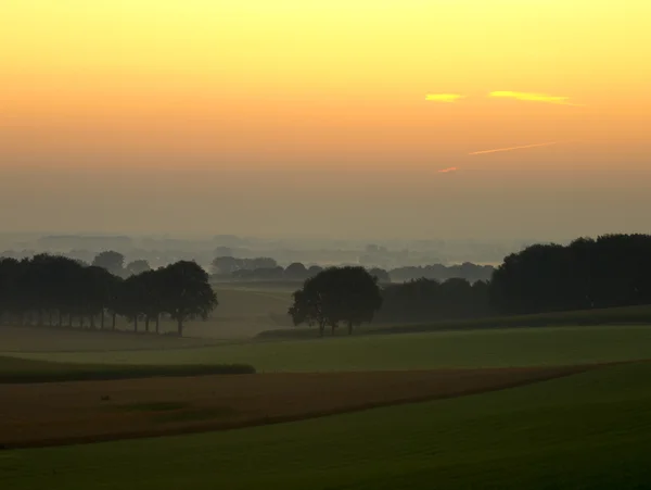 Dunst in landwirtschaftlichen Hügeln kurz vor Sonnenaufgang — Stockfoto